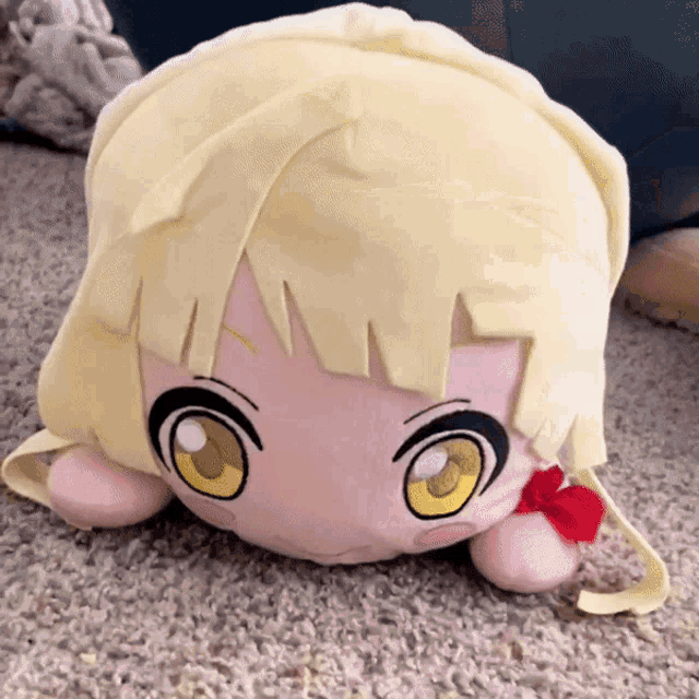a stuffed doll with blonde hair and yellow eyes is laying on a carpet
