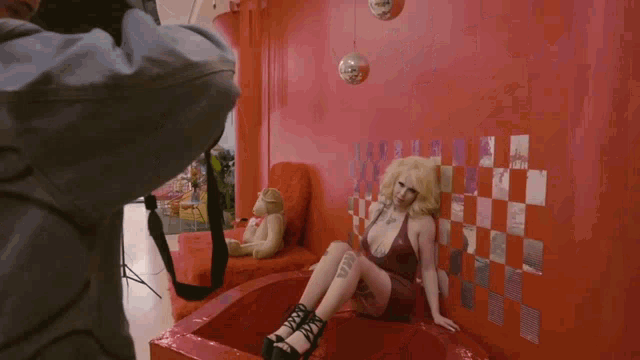 a woman in a red dress is being photographed by a man with a camera