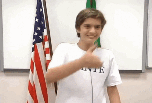 a boy wearing a white shirt with the word inte on it is giving a thumbs up
