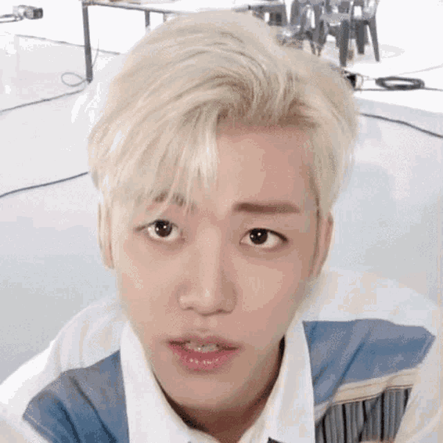 a close up of a young man 's face with blonde hair and a blue shirt .