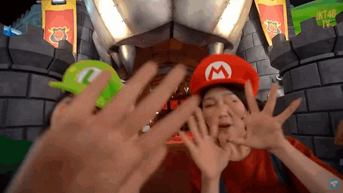 a person wearing a mario hat making a face with their hands