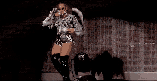 a woman is singing into a microphone while wearing a striped top and thigh high boots