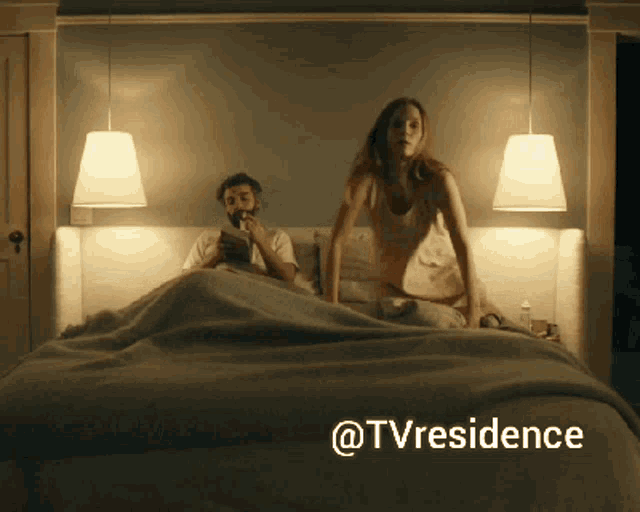 a man is reading a book while a woman is standing on a bed with @tvresidence written on the bottom