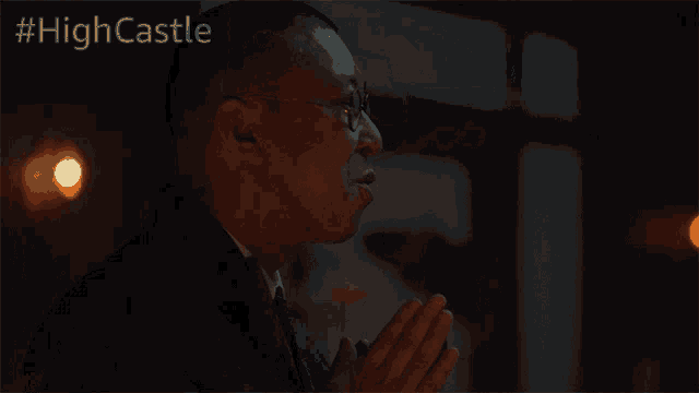 a man in a suit and tie is in a dark room with #highcastle written on the bottom right