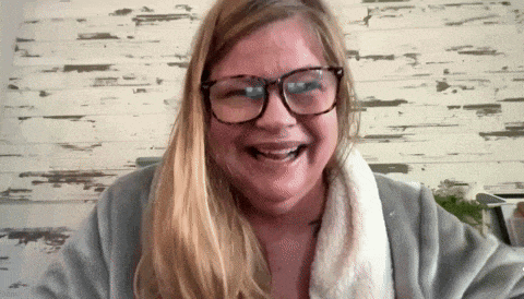 a woman wearing glasses and a robe is smiling and laughing
