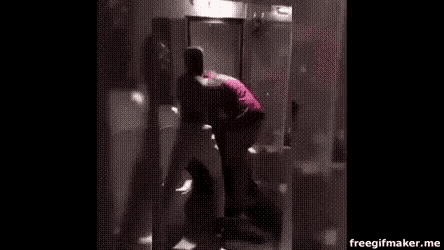 a man is standing in a bathroom next to a toilet and looking at himself in the mirror .