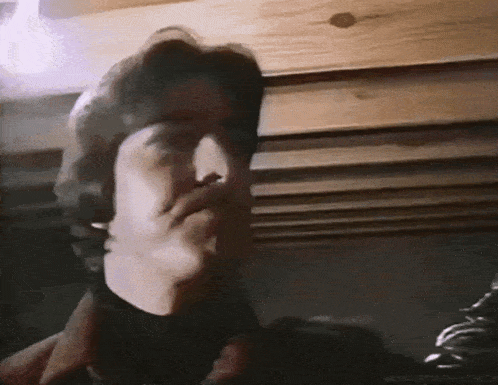 a man wearing headphones is making a funny face in a dark room .