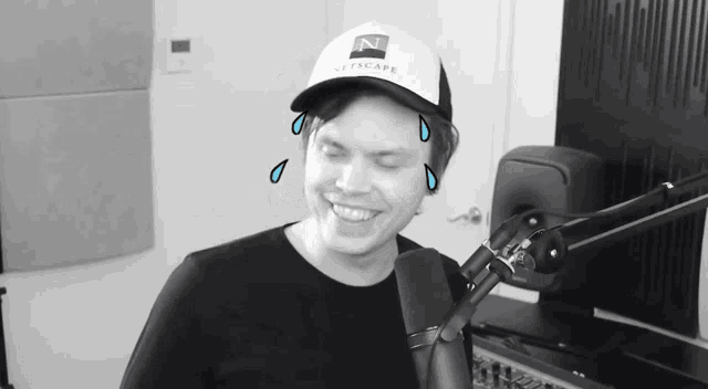 a man wearing a hat that says netscape is smiling in front of a microphone