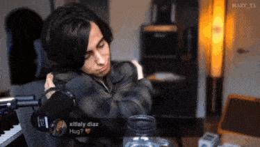 a man sitting in front of a microphone with a message from xitaly diaz hugging