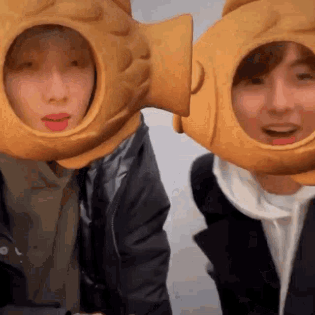 two people wearing fish hats are standing next to each other .