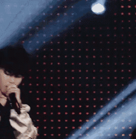 a person is singing into a microphone in front of a wall of lights
