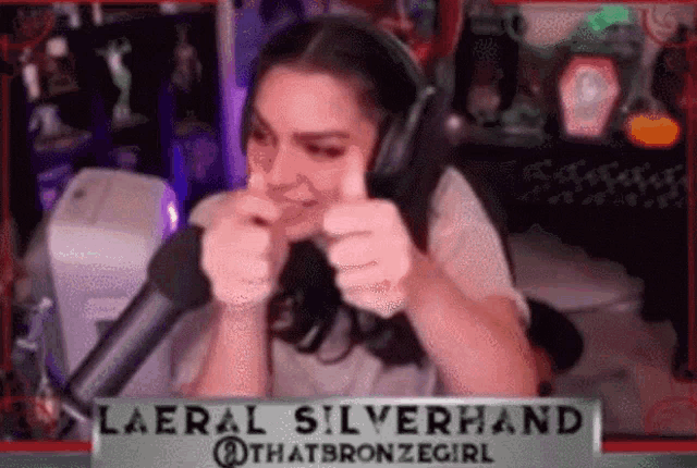 a woman is giving a thumbs up in front of a microphone while wearing a headset .