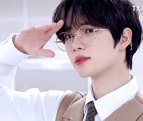 a close up of a person wearing glasses and a white shirt with the letter t on it