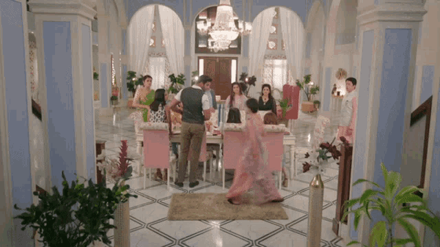 a group of people are gathered around a dining table in a large room