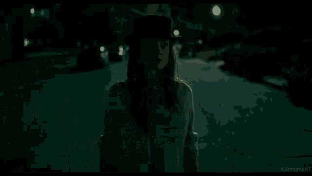 a woman in a top hat is walking down a dark street .