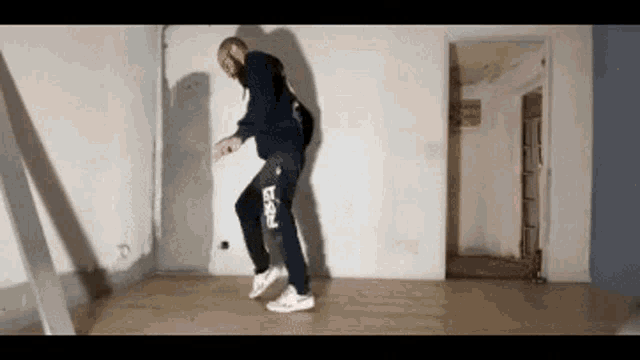 a man is dancing in an empty room with a shadow on the wall behind him