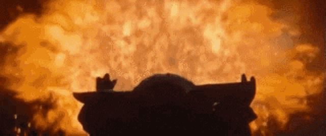 a person is standing in front of a large explosion of fire .