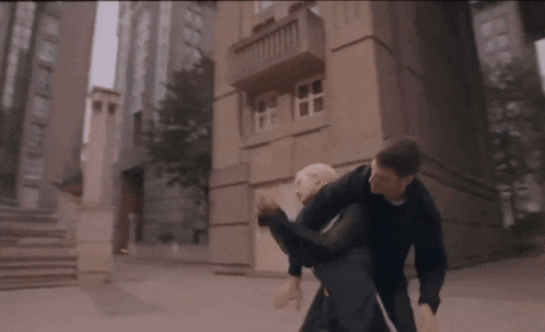 a man is carrying another man on his shoulders in front of a building