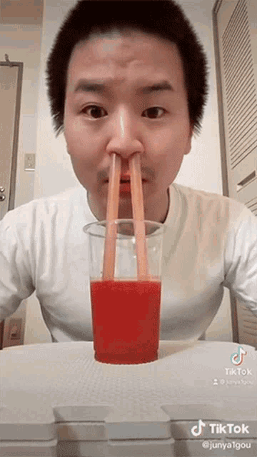 a man with two straws sticking out of his nose drinking a cup of juice