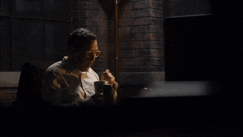 a man sits at a table with a cup that says ice cream
