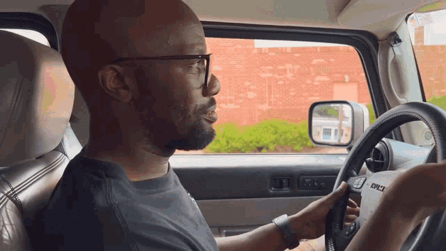 a man wearing glasses is driving a hummer jeep