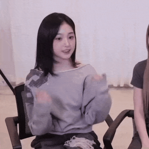 a woman in a gray sweater is sitting in a chair