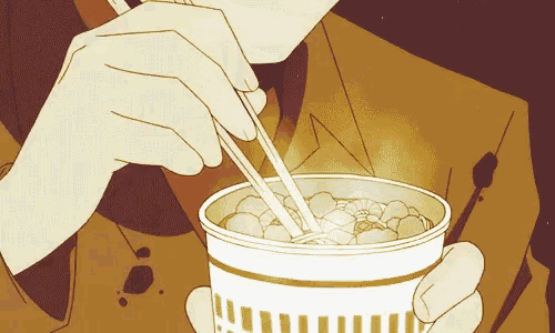 a person is eating noodles from a cup with chopsticks .