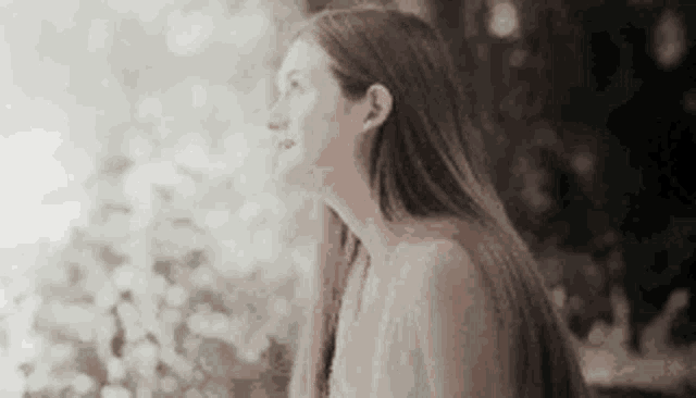 a woman with long hair is sitting in front of a window looking up .