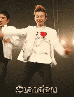a man in a white jacket is dancing with another man in a black shirt with a heart on it .