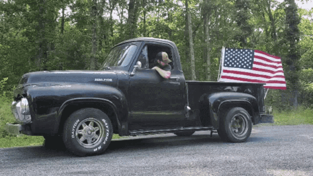 a black pickup truck with dayton tires and an american flag on the back
