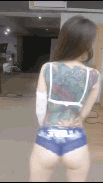 a woman with tattoos on her back is wearing blue shorts
