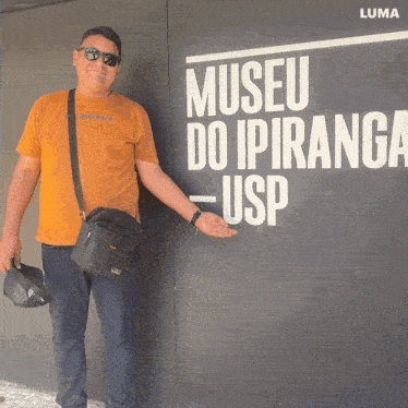 a man stands in front of a sign that reads museu do ipiranga usp