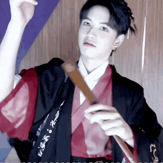 a man in a red and black kimono is holding a sword