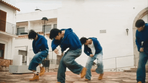 a man in a blue hoodie is dancing in front of a white building with a sign on it that says mexican culture