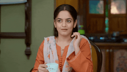 a woman sitting at a table holding a cup of coffee