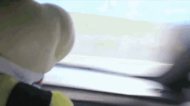 a person is looking out a car window with a yellow hat on