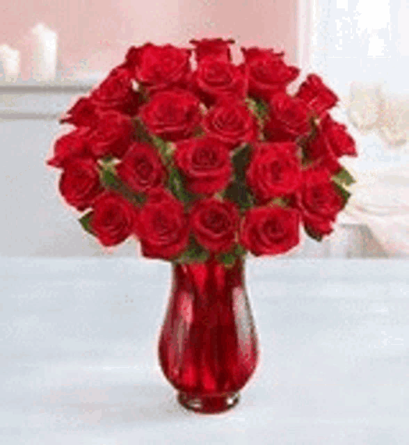 a red vase filled with red roses on a table .