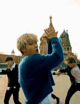 a group of young men are dancing in front of a large building