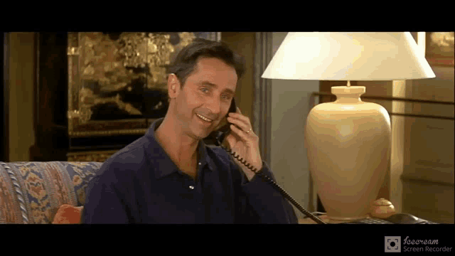 a man is smiling while talking on a phone