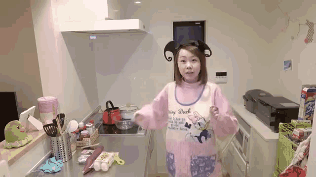 a woman in a kitchen wearing a pink apron that says mickey duck