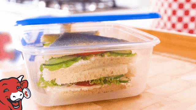 a sandwich in a plastic container with a cow behind it that says the laughing cow
