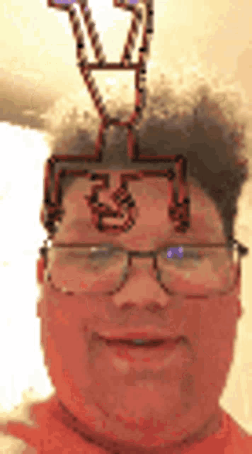 a man wearing glasses and a necklace on his head is smiling .