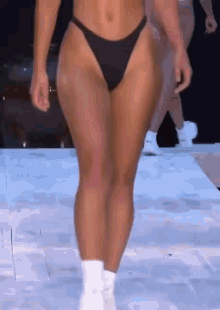 a woman in a bikini is walking down the runway .