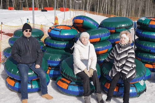 a man and two women sit on a pile of tubes