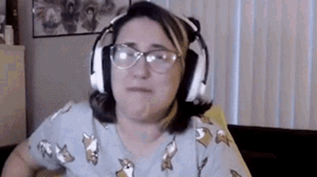 a woman wearing headphones and glasses is sitting in front of a computer screen .
