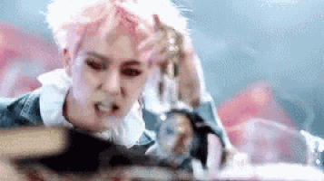 a woman with pink hair and red eyes is sitting at a table with a knife in her hand .