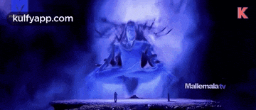 a man is standing in front of a statue of shiva in a purple light .