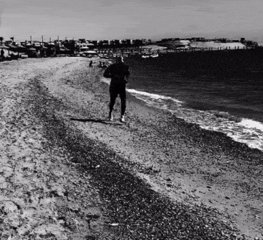a man is running on the beach near the water