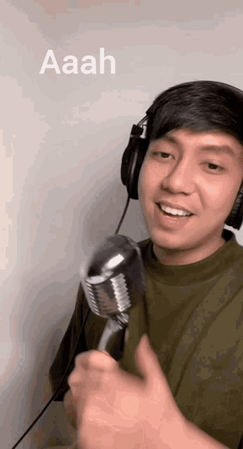 a man wearing headphones is singing into a microphone and the word aaah is above him