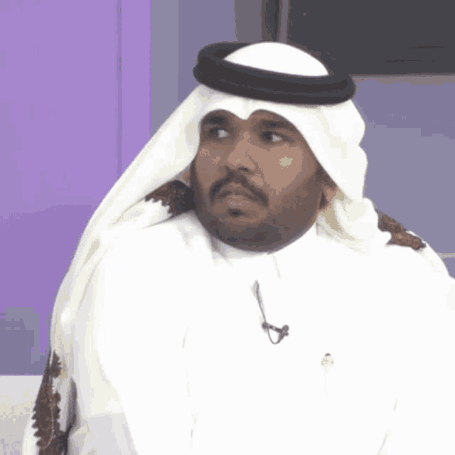 a man wearing a turban and a white shirt has a microphone attached to his neck